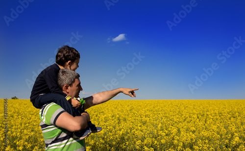 Child on the shoulders of his father in rapseed plantation,  photo