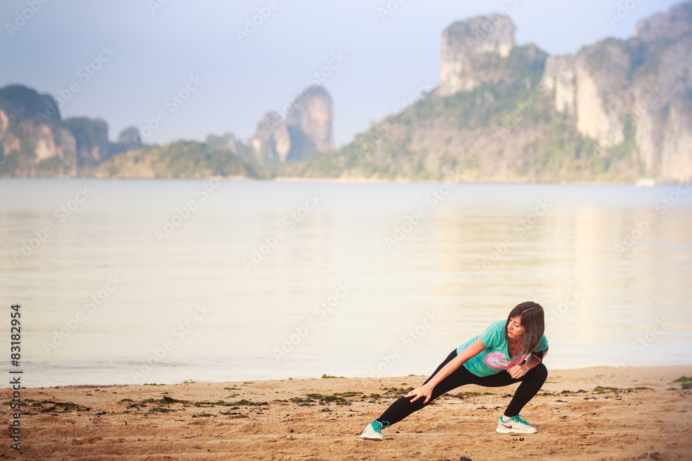 Naklejka premium girl does gymnastics on beach at dawn