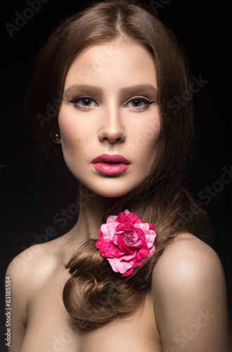 Beautiful girl with pink lips and a rose in her hair.