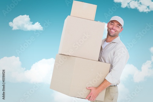 Composite image of delivery man carrying cardboard boxes photo