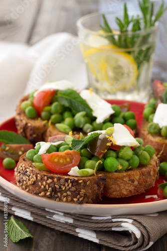 Green peas with cherry tomatoes, feta cheese and mint on toast