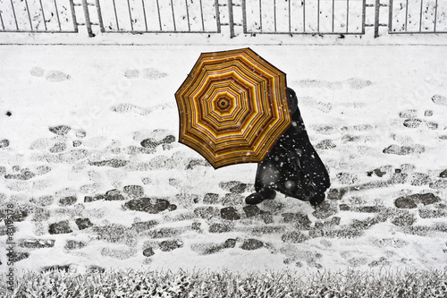 Spacer po chodniku z parasolem w opadach śniegu
