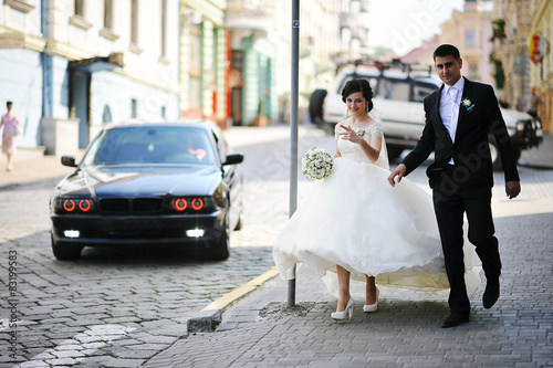 walking newlyweds on backqround black car photo