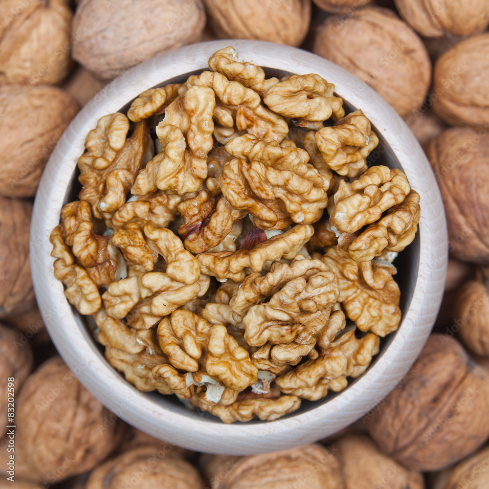 Walnuts in a wooden bowl on a walnuts pile Walnuts in a wooden bowl on a walnuts pile