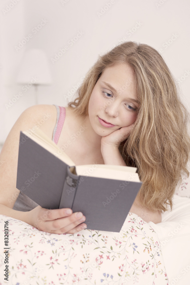 Beautiful young woman reading book in bed Beautiful young woman reading book in bed