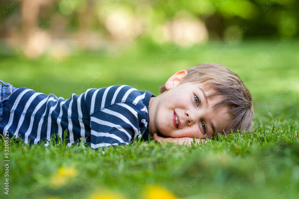 Smiling little boy lying on the grass in the park Smiling little boy lying on the grass in the park
