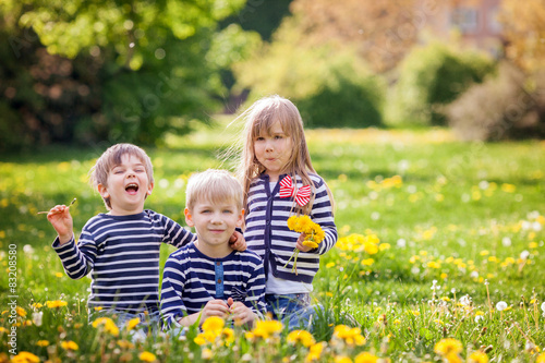 Three adorable kids, dressed in striped shirts, hugging and smil