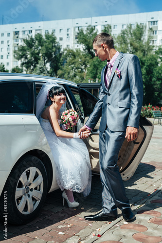Happy groom helping his bride out of the wedding car © andreiko