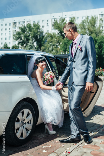Happy groom helping his bride out of the wedding car © andreiko