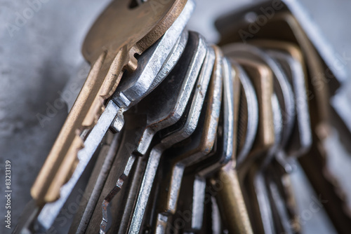 A bunch of old worn keys on the grey concrete wall