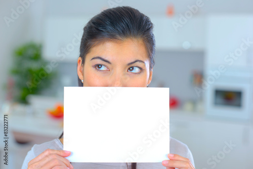 Woman holding sheet of paper over her mouth