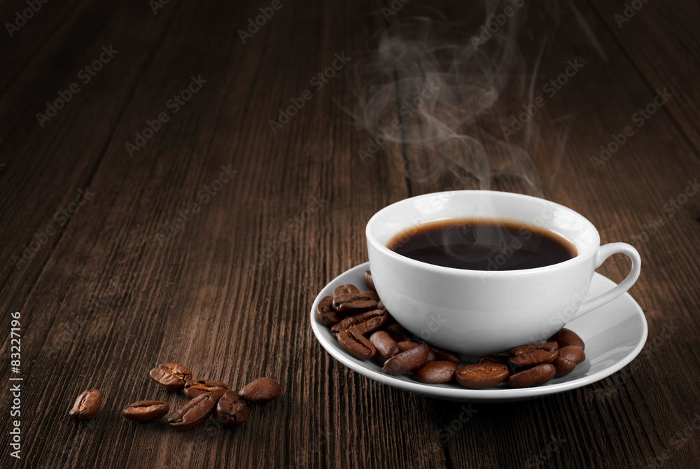 Fototapeta premium Cup of hot coffee on a wooden table. Coffee beans. Steam.