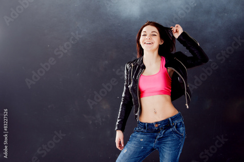 young woman hip hop dancer on the background texture dark wall