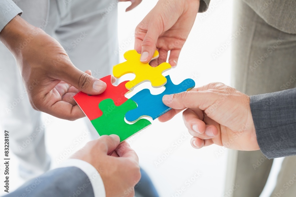 Business colleagues holding piece of puzzle Business colleagues holding piece of puzzle