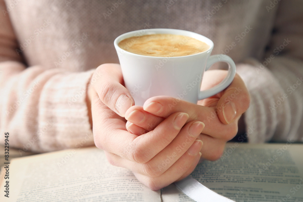 Woman holding cup of coffee and read the book, close up Woman holding cup of coffee and read the book, close up