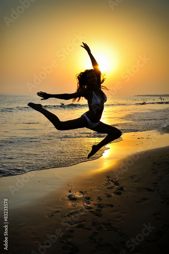 Happy Woman Jumping in Sea Sunset