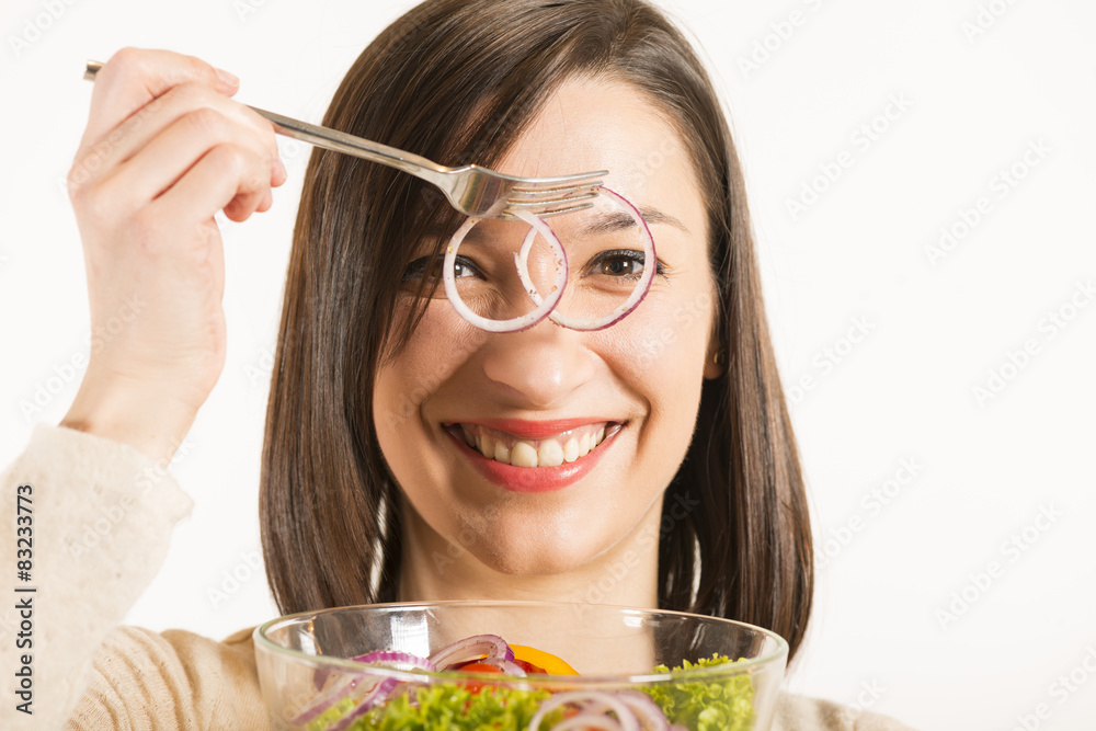 Woman looking through sliced onion having bowl of salad in hand Woman looking through sliced onion having bowl of salad in hand
