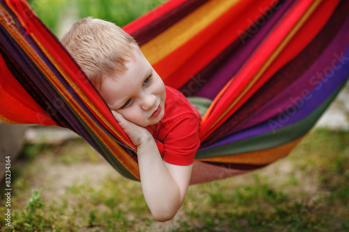 Beautiful cheerful little boy resting in a hammock