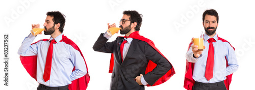 Hipster businessman dressed like superhero drinking orange juice