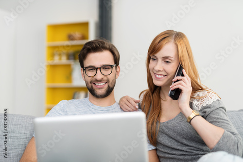 glückliches paar mit laptop und telefon zu hause