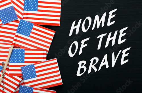 The phrase Home of the Brave with USA flags on a blackboard