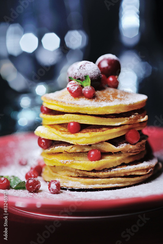 Stack of pancakes with berries and sugar powder