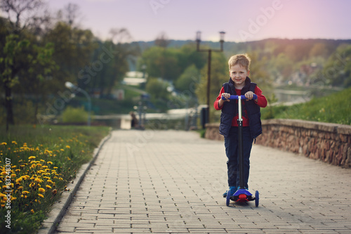 Little  boy riding and his scooter bicycle in summer  outdoors