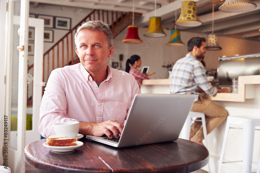 Middle aged man using laptop in a cafe Middle aged man using laptop in a cafe