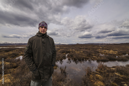 Fotografie, Obraz Man traveler on marshland against the backdrop of rain clouds.