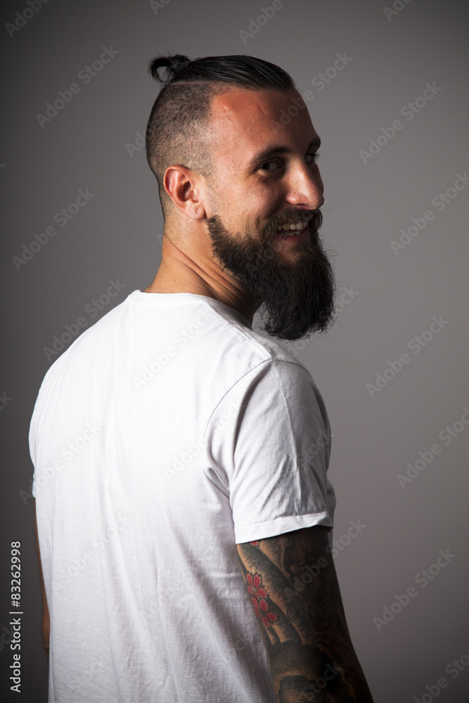 Hipster con camiseta blanca y brazo tatuado sonriendo