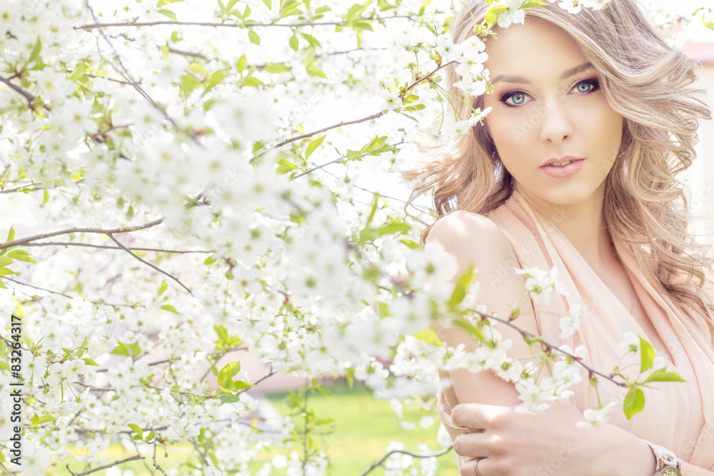 Fototapeta premium sweet girl in a light dress walking in a lush cherry orchard