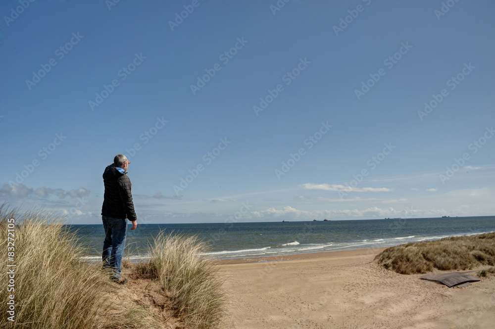 Man standing at a viewpoint overlooking a beach