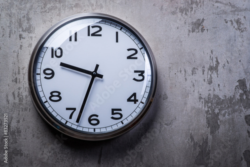 Round wall clock hanging on the grey concrete wall