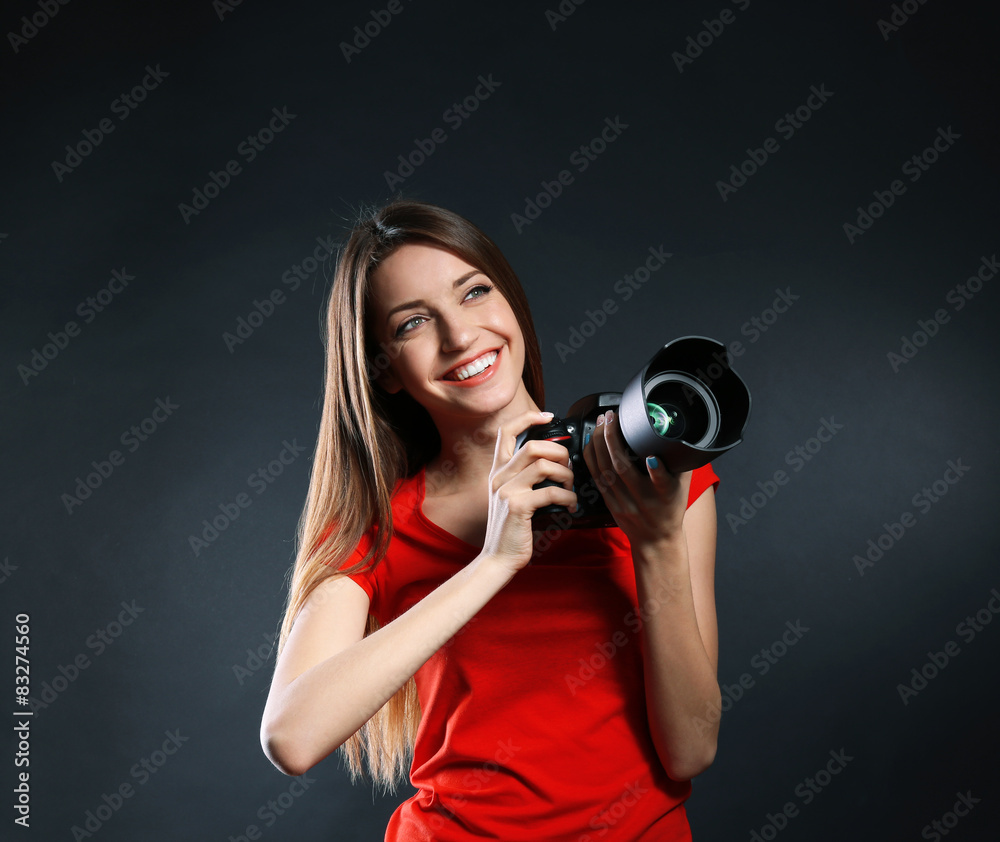 Obraz premium Young female photographer taking photos on black background
