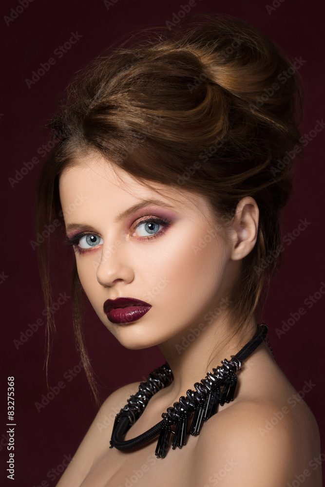 Young pretty girl with vinous lipstick at dark red background