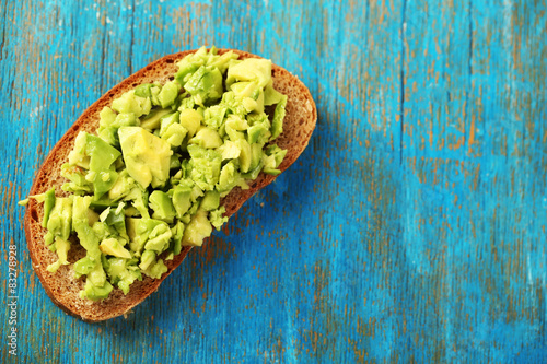 Slice of rye bread with guakomole avocado on color wooden background photo