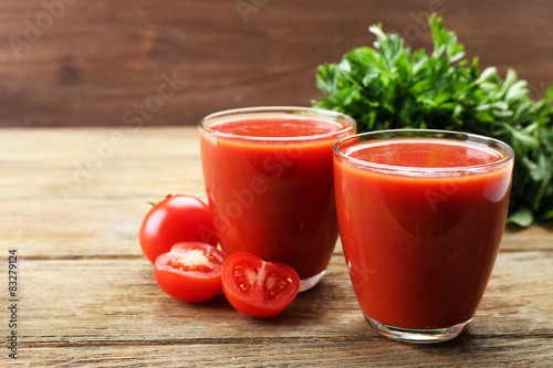 Glasses of fresh tomato juice on wooden background