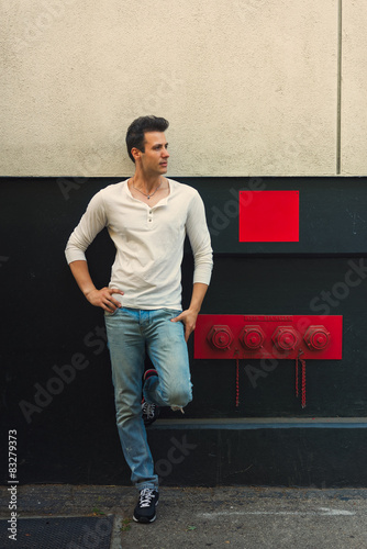 Handsome casual serious man lean back wall, looking away.