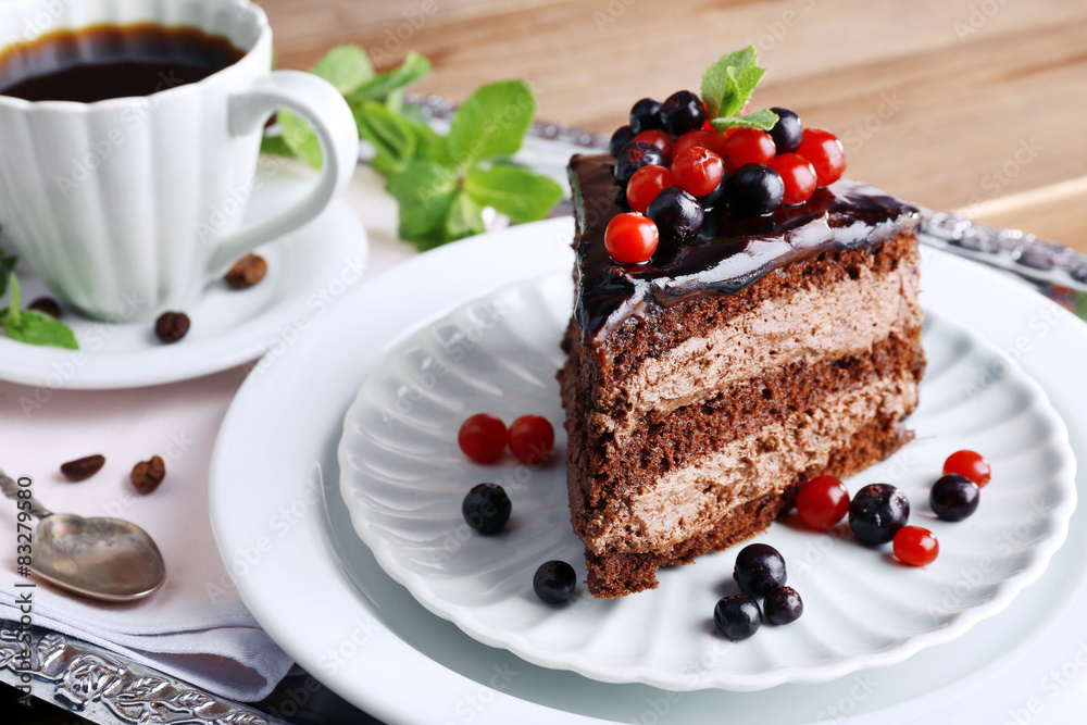 Delicious chocolate cake with berries and cup of coffee on table close up Delicious chocolate cake with berries and cup of coffee on table close up
