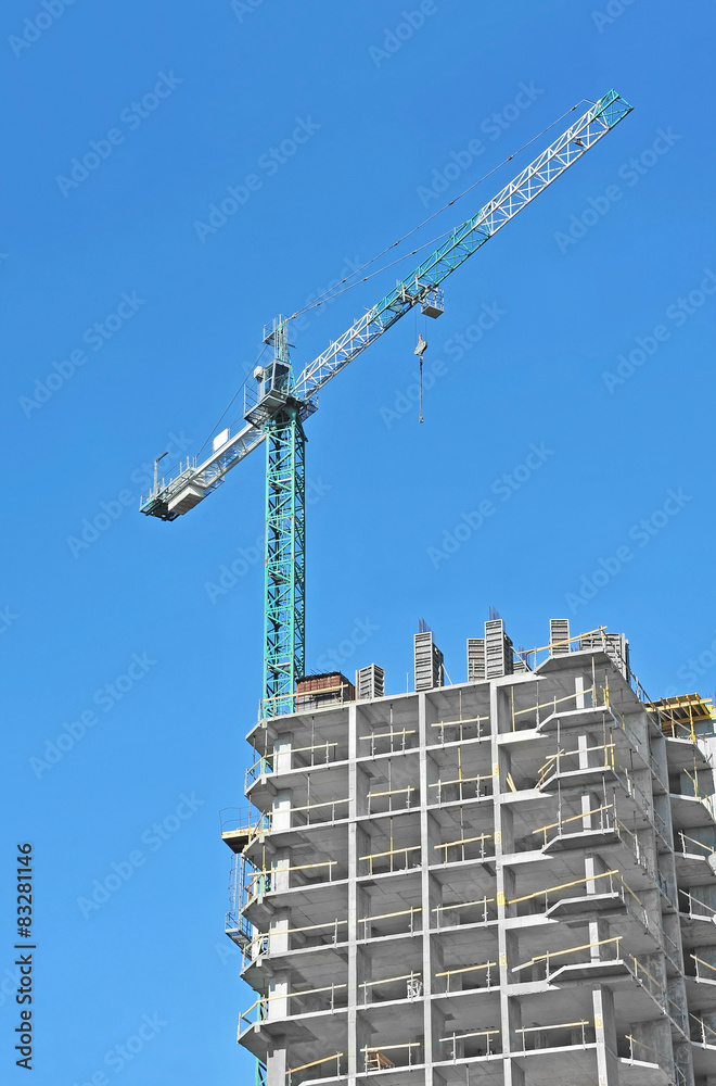 Crane and building construction site against blue sky