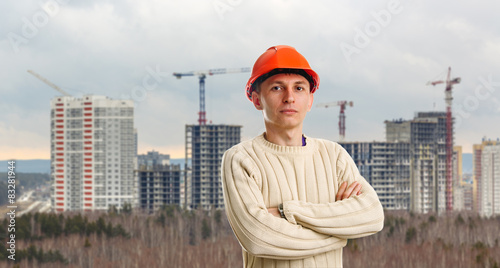 Workman in red helmet on background of buildings