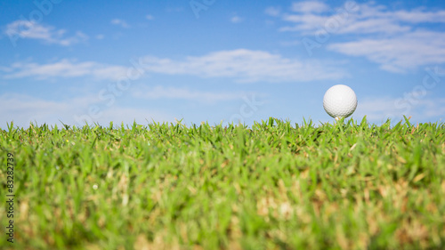 Golf ball on grass with sky background
