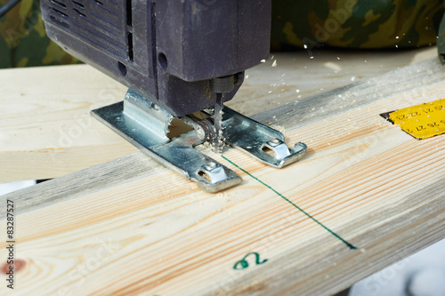 Electrofret saw is sawing wooden board photo