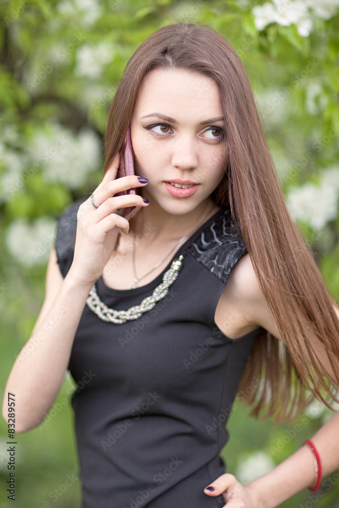 Young woman with smartphone on blooming lilac background Young woman with smartphone on blooming lilac background