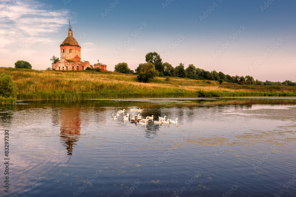 Rural country landscape with an old church and a pond with geese in summer in the village, Russia Rural country landscape with an old church and a pond with geese in summer in the village, Russia