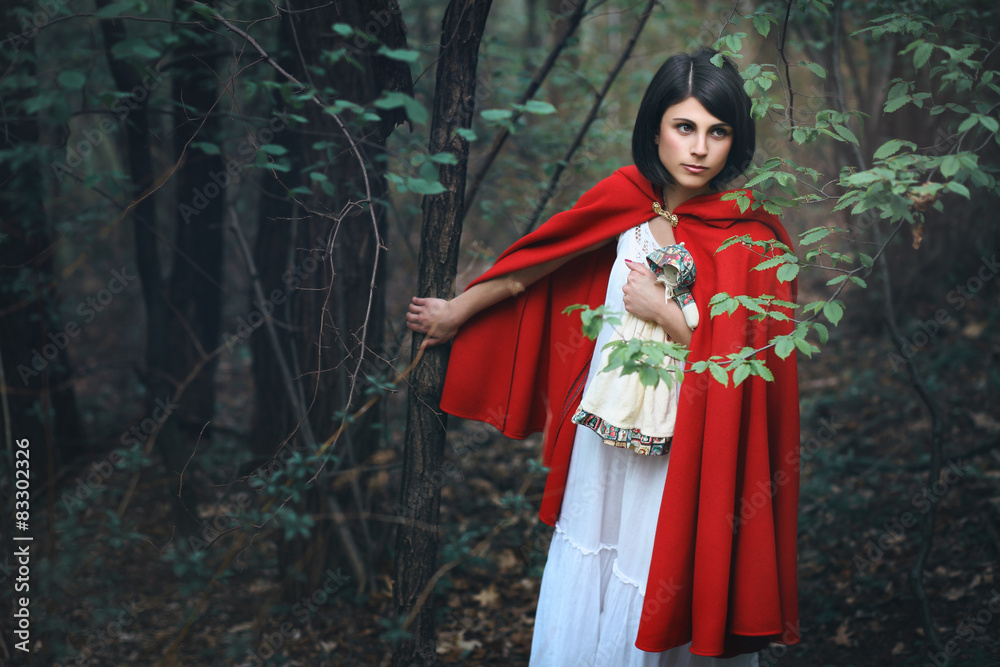 Beautiful woman with red mantle in a dark forest