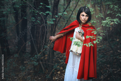 Beautiful woman with red mantle in a dark forest