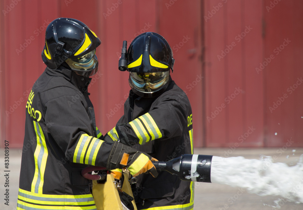 Fototapeta premium two firemen in action with foam