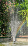 Fountain with rainbow in public park 