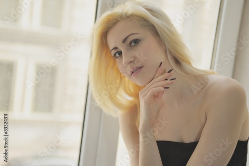 Portrait close up of young beautiful blonde woman near window